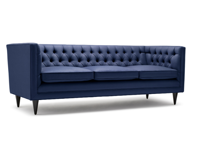 A modern, navy blue, tufted sofa with three seat cushions and tapered wooden legs.