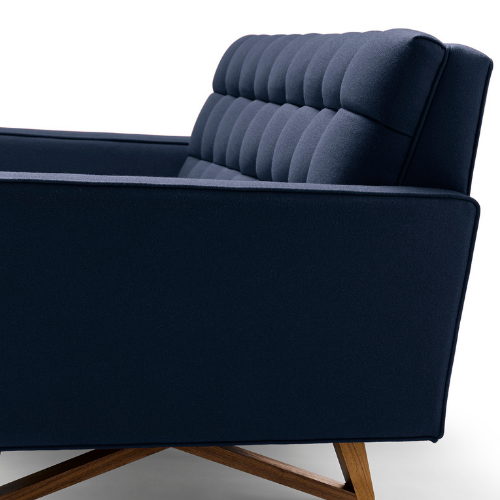 A modern navy blue couch with a tufted backrest and wooden legs.