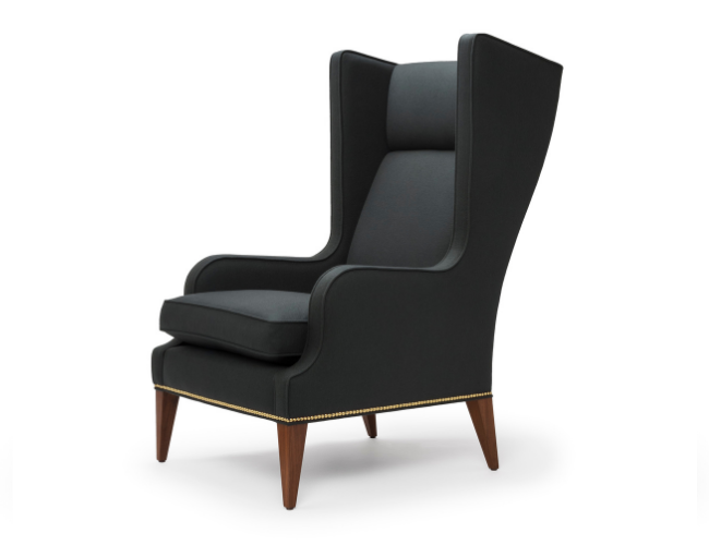 Black wingback armchair with wooden legs and nailhead trim details.