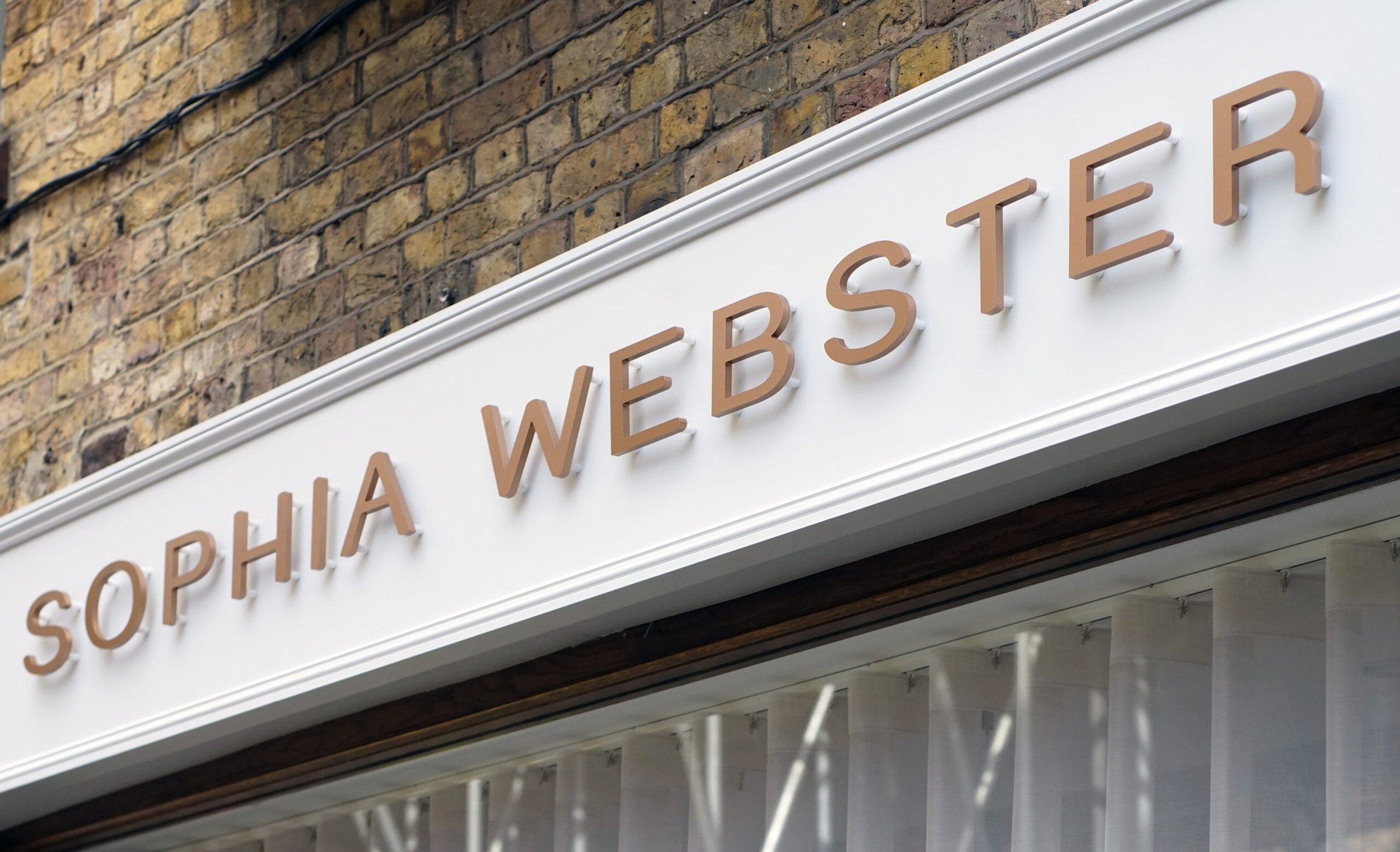 Storefront with a brick facade and a white sign displaying the words 'SOPHIA WEBSTER' in beige 3D letters.