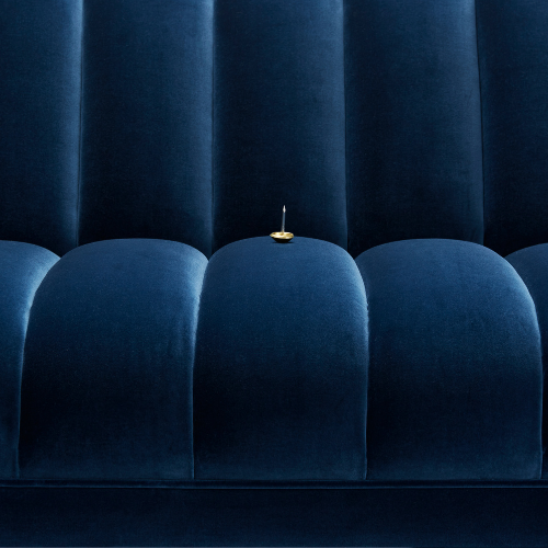 Close-up of blue velvet theater seats with a gold and black item placed on one of the seats