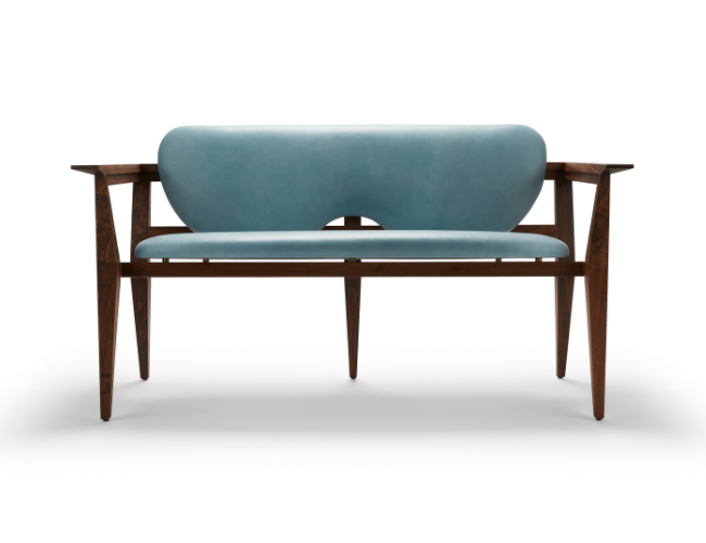 A mid-century modern bench with a blue upholstered seat and backrest, wooden armrests, and tapered wooden legs.