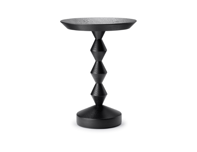 Black wooden side table with a round top and sculptural, stacked geometric base.