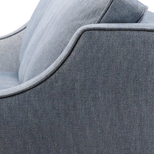 Close-up of a light gray upholstered armchair with a curved armrest.