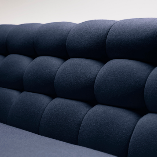 Close-up of a navy blue upholstered sofa with rounded, tufted cushions.