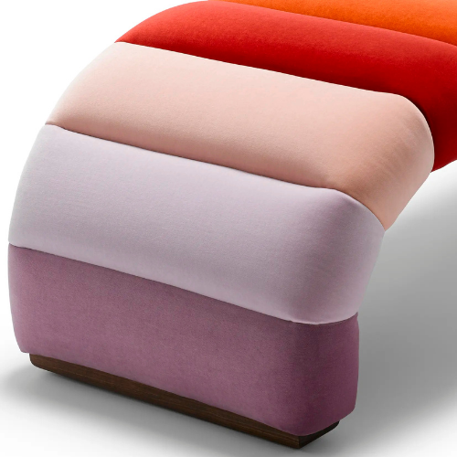 Colorful upholstered ottoman with four cushioned sections in shades of purple, white, pink, and red with a wooden base.