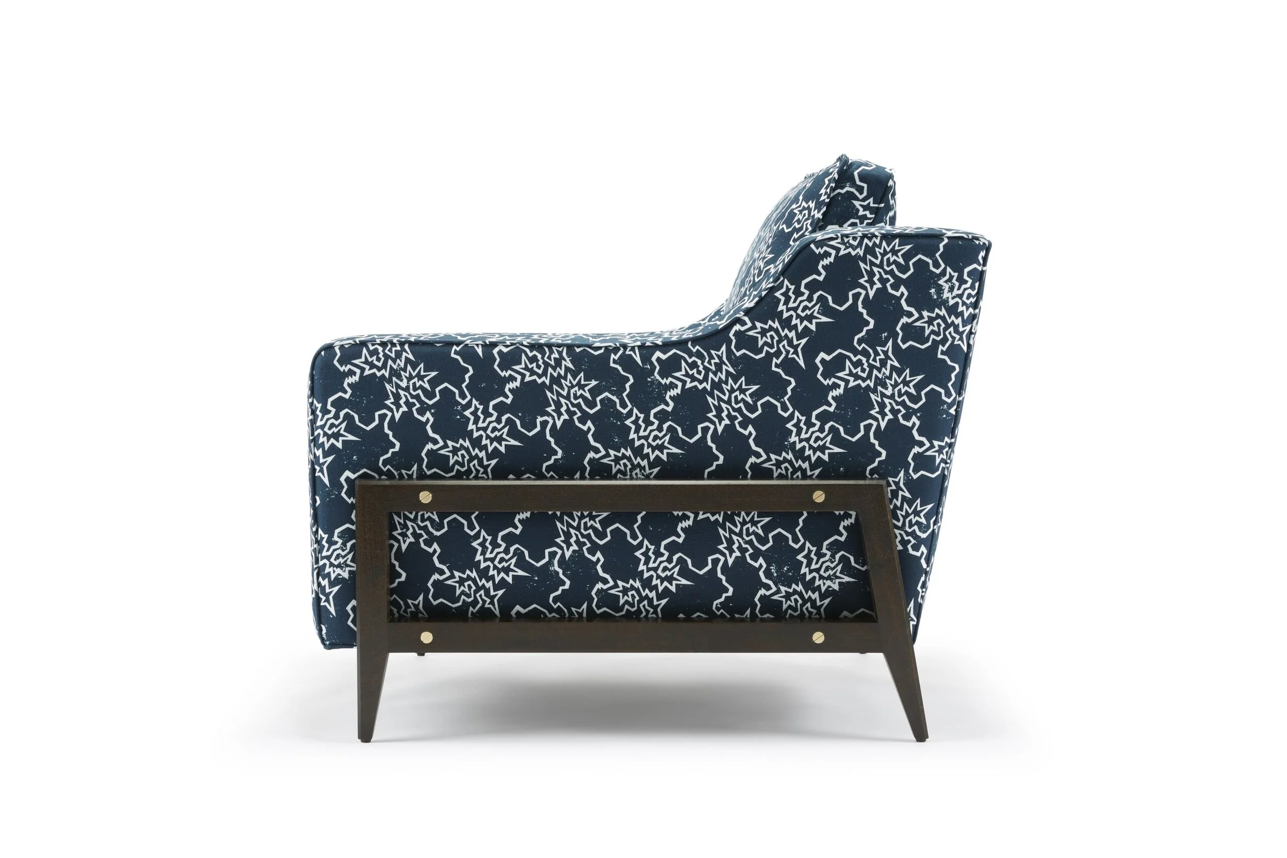 A modern accent chair with a navy blue and white star and zigzag patterned fabric upholstery, wooden legs, and a slightly reclined backrest.