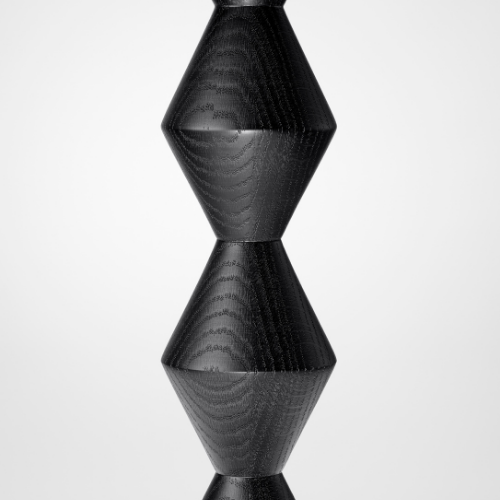 A black wooden sculpture with three geometric shapes stacked vertically, each with a conical base, on a white background.