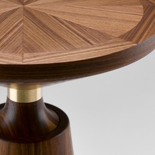 Close-up view of a wooden table's corner, showcasing a geometric pattern in the wood grain and a rounded edge.