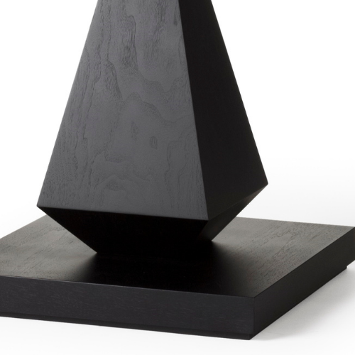A black geometric sculpture on a flat black base against a white background.