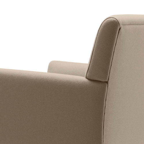 Close-up of a beige upholstered armchair with a curved backrest and armrest on the right side.