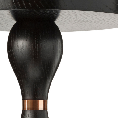 Close-up of a black wooden table leg with a copper accent at the base.