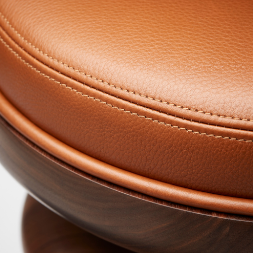 Close-up of a brown leather chair with detailed stitching and wood base.