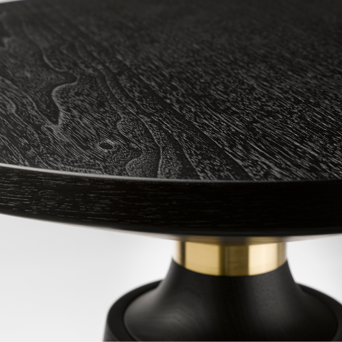 Close-up of a black wooden table with a textured wood grain pattern, supported by a black and gold pedestal base.