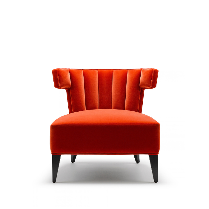A modern red velvet armchair with vertical stitching on the backrest, black tapered legs, and a high back, set against a plain white background.