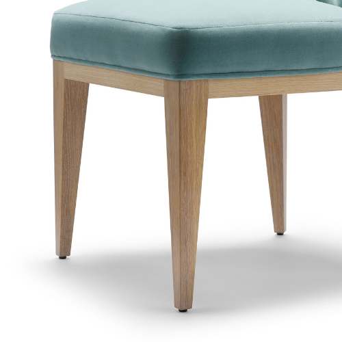 Close-up of a piece of furniture with a light blue upholstered seat and wooden legs.