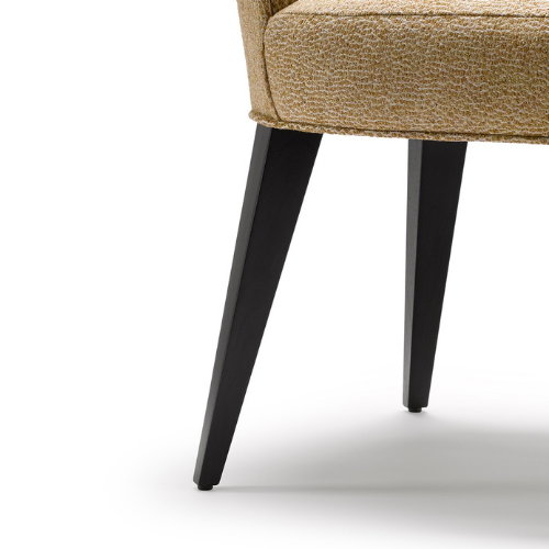 Close-up of a beige upholstered chair with black tapered wooden legs on a white background.