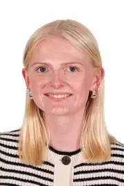 A woman with blonde hair, wearing a black and white striped top, smiling at the camera.