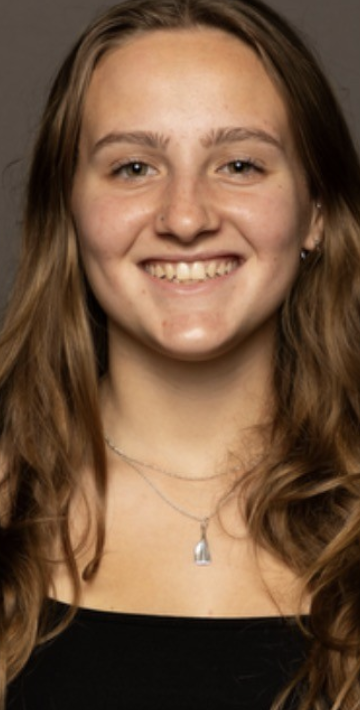 A young woman with long, wavy brown hair smiling at the camera.
