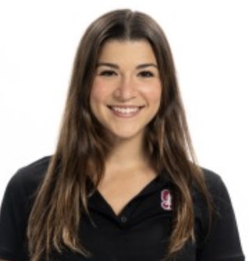 A young woman with long brown hair smiling, wearing a black polo shirt with a small logo on the left side, against a white background.