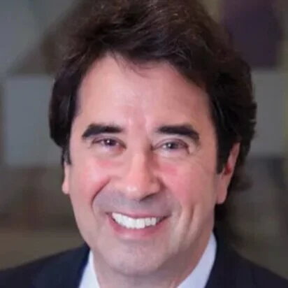 Headshot of a smiling man with dark hair and wearing a suit.