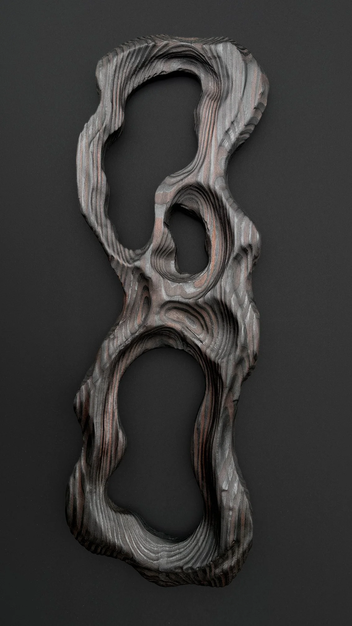 An abstract wooden sculpture with multiple hollowed-out sections, placed on a dark background.