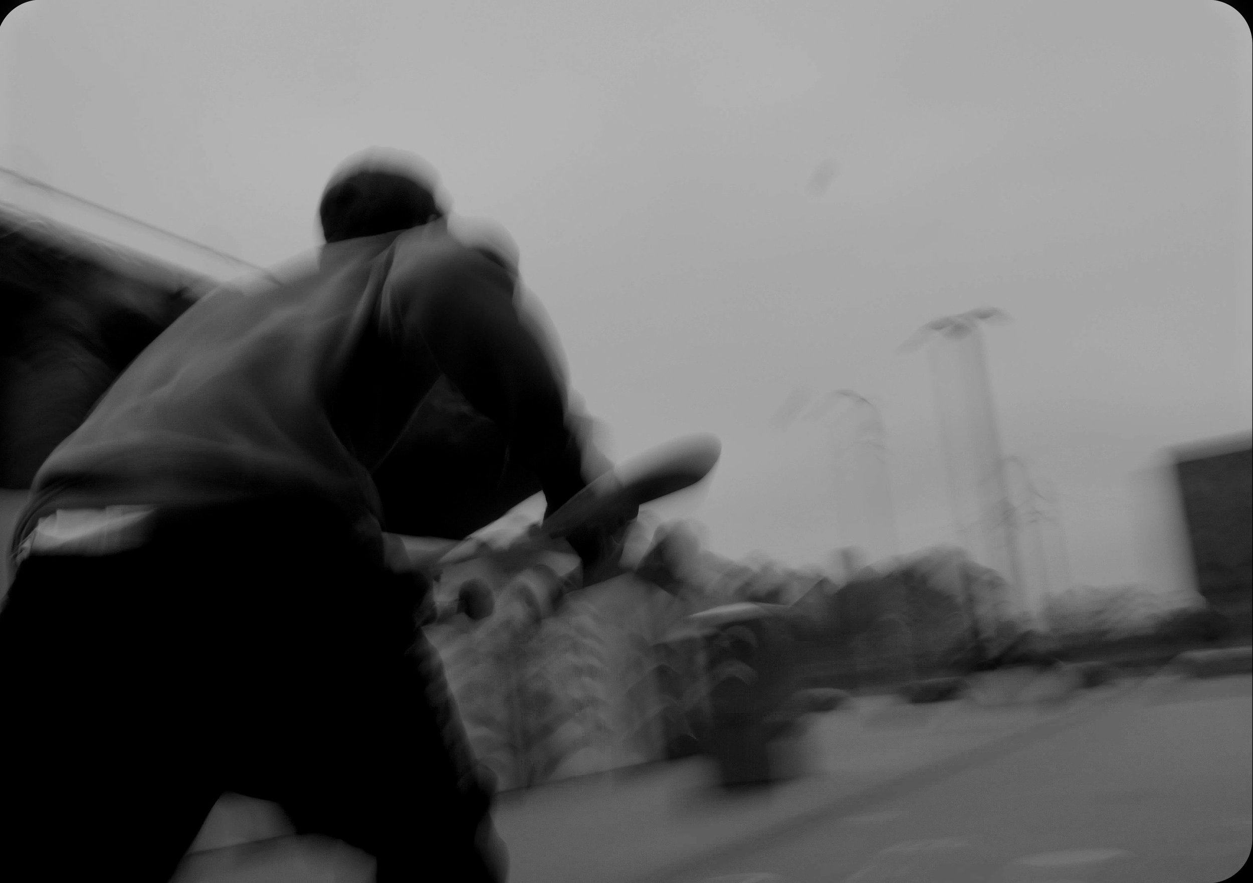 A person in dark clothing is seen from below, reaching out with their hand, with a cloudy sky and streetlights in the background.