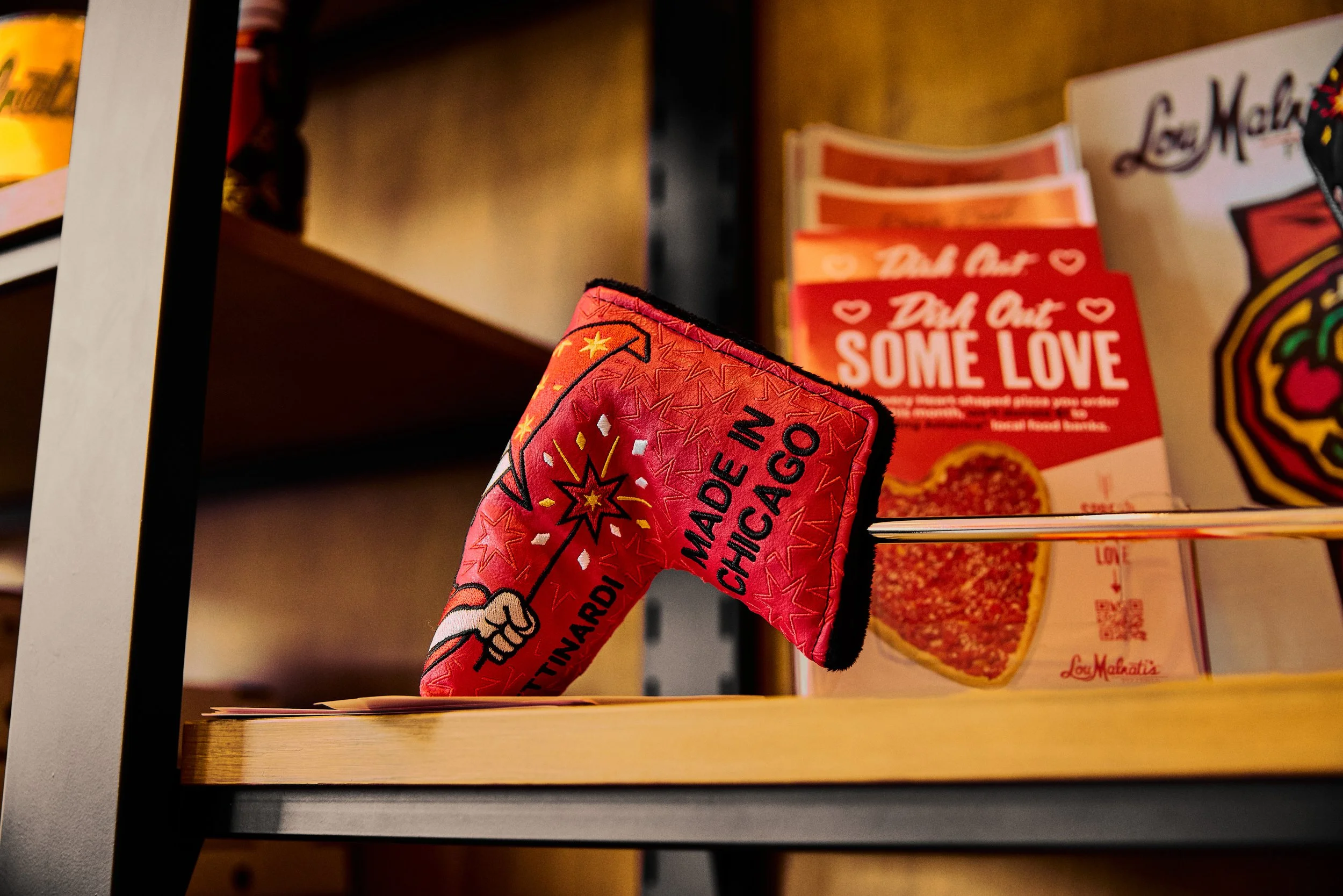 A decorative novelty item resembling a red firecracker or rocket with the text "Made in Chicago" and related graphics, displayed on a wooden shelf in a store.