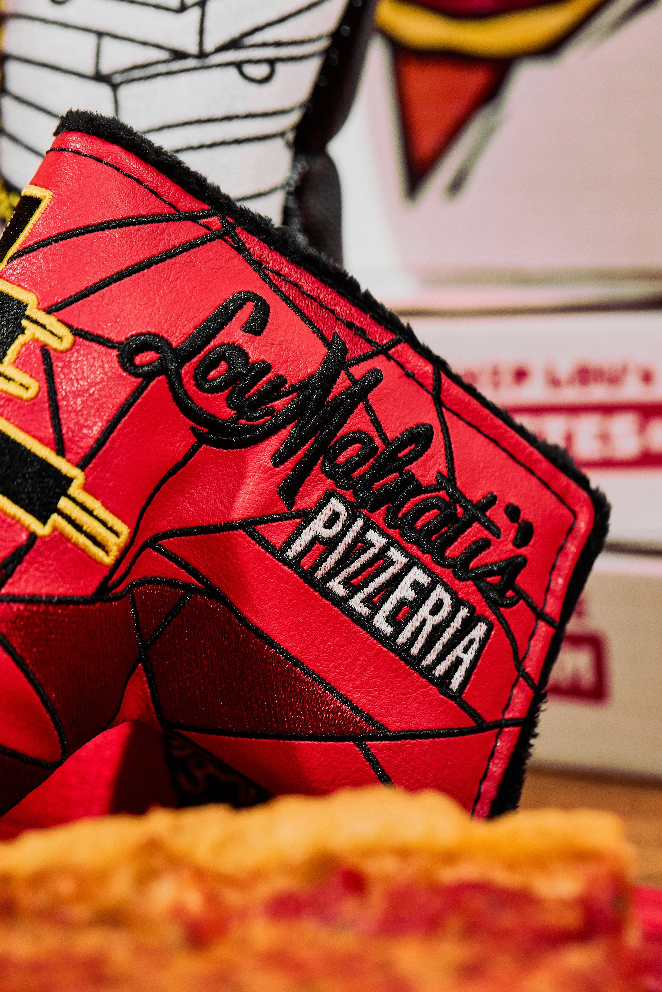 Close-up of a red patch with black embroidery that says 'Streetwear.' Part of a white and black striped garment is visible in the background.