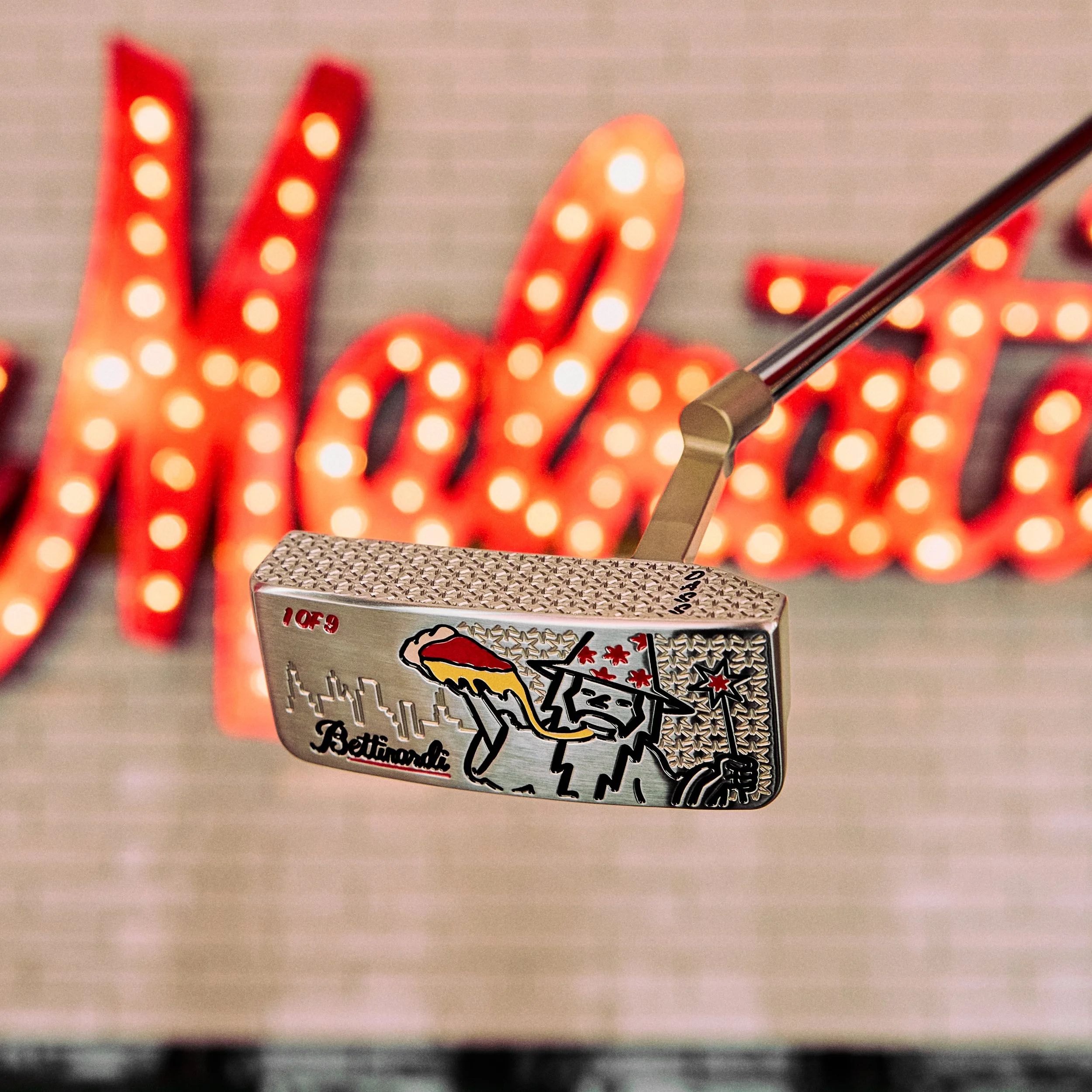 Close-up of a souvenir box featuring a graphic of Bettina, a hot dog, and fireworks, with part of a stick or utensil visible.
