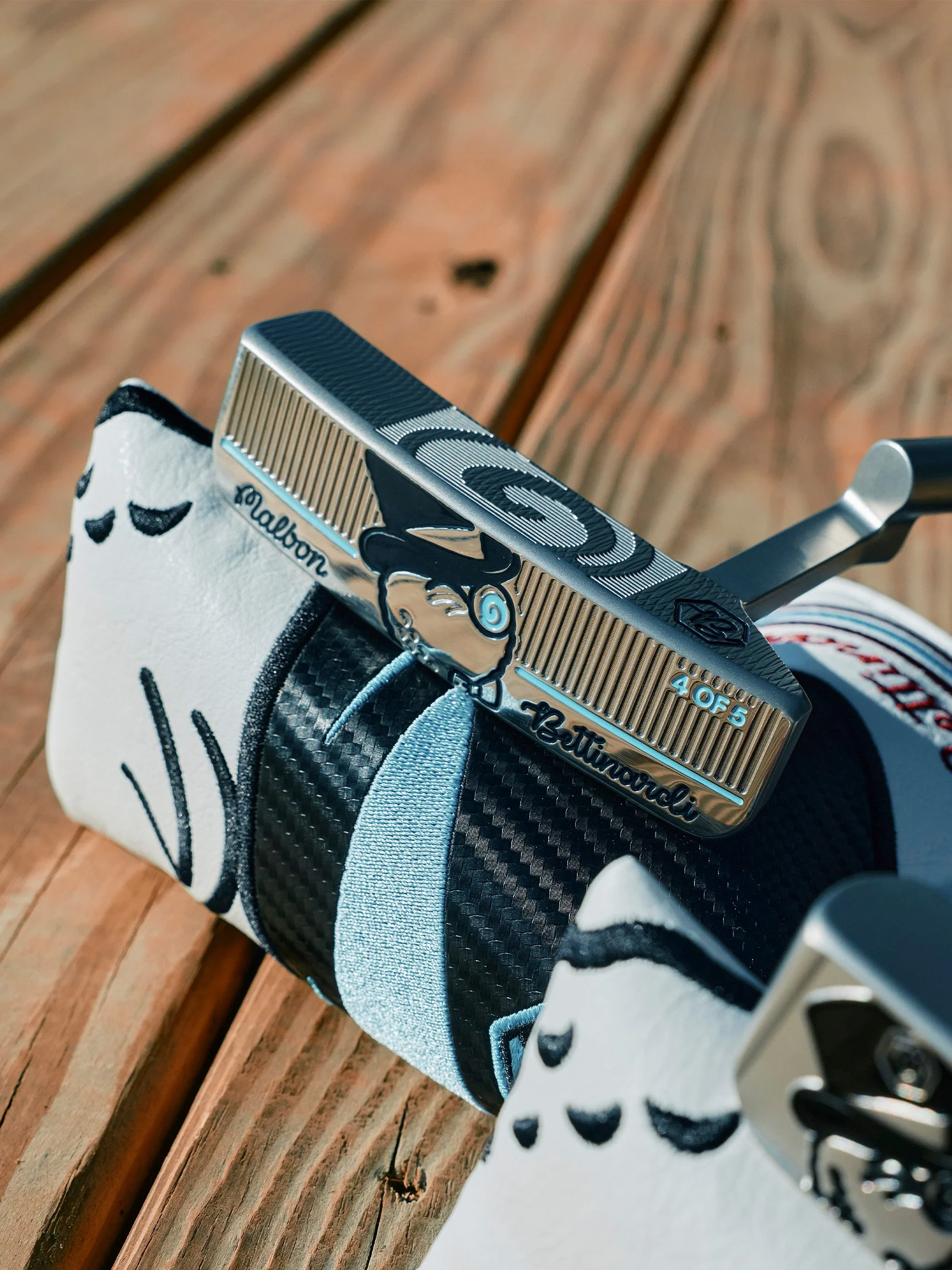 Close-up of a golf club resting on a white glove with black polka dots, placed on a wooden surface.