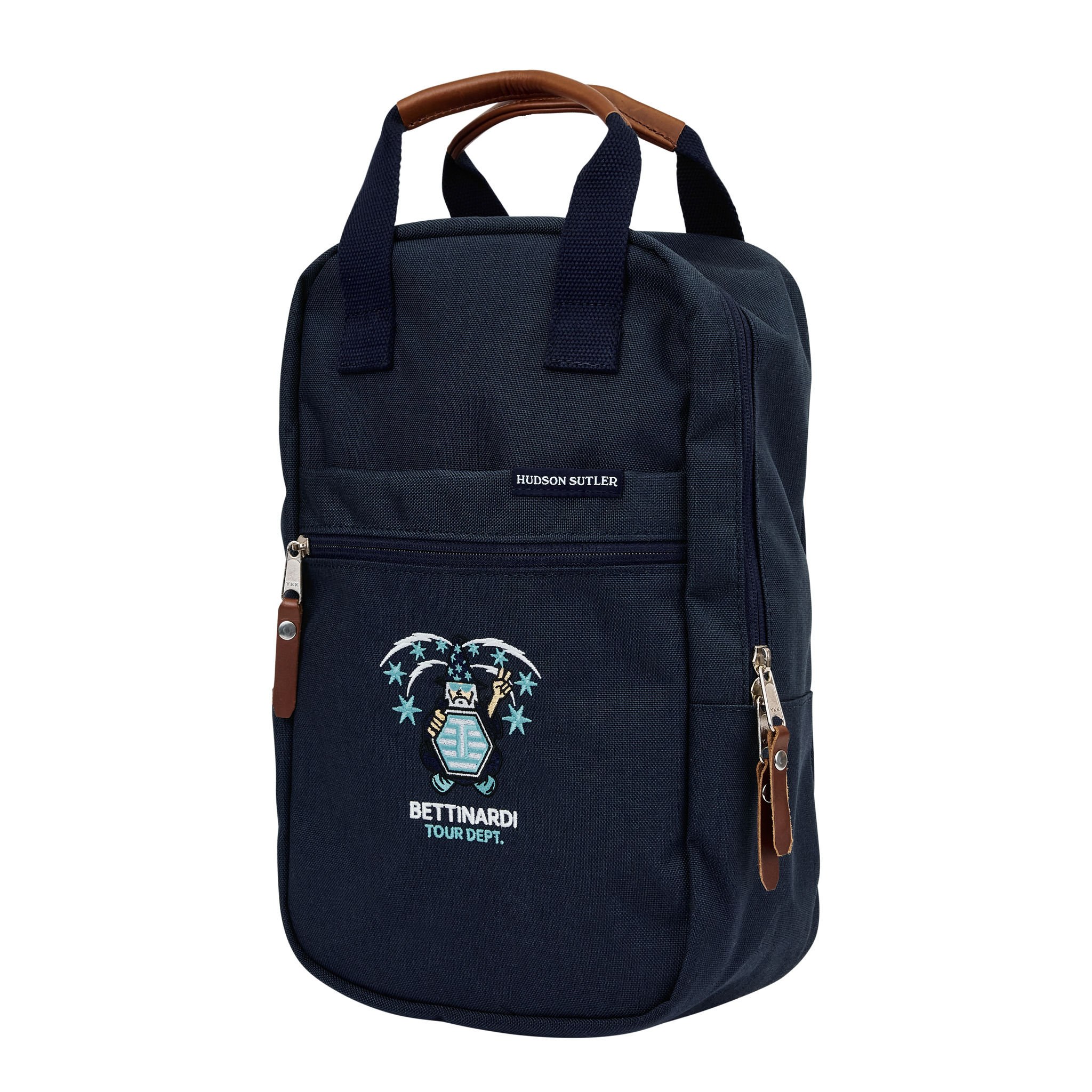 A navy blue backpack with brown leather handles and accents featuring an embroidered image of a skeleton with tropical flowers and the text 'BETTENDORF TOUR DEPT.'