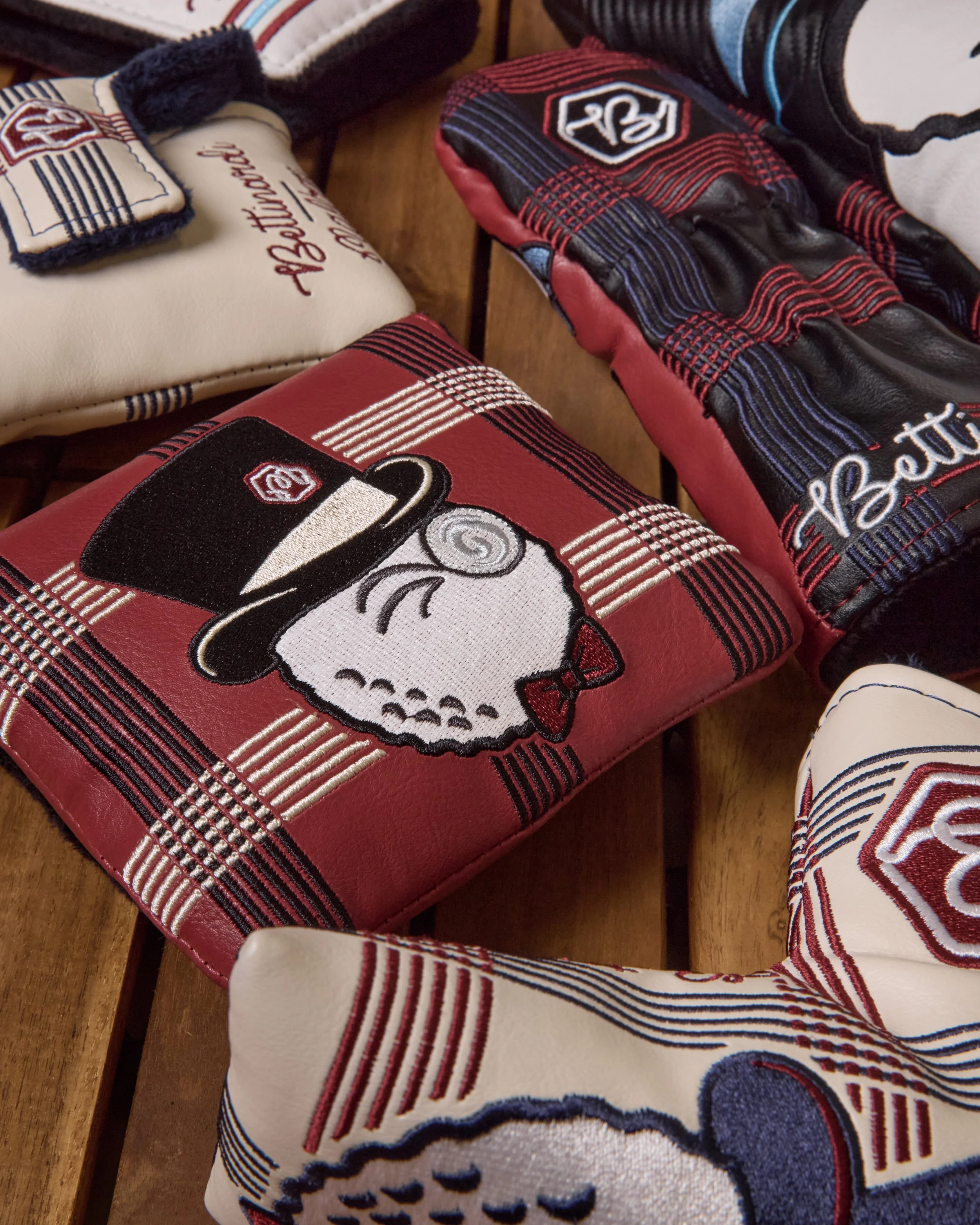 Close-up of vintage baseball gloves and a towel with baseball-related illustrations and branding, placed on a wooden surface.