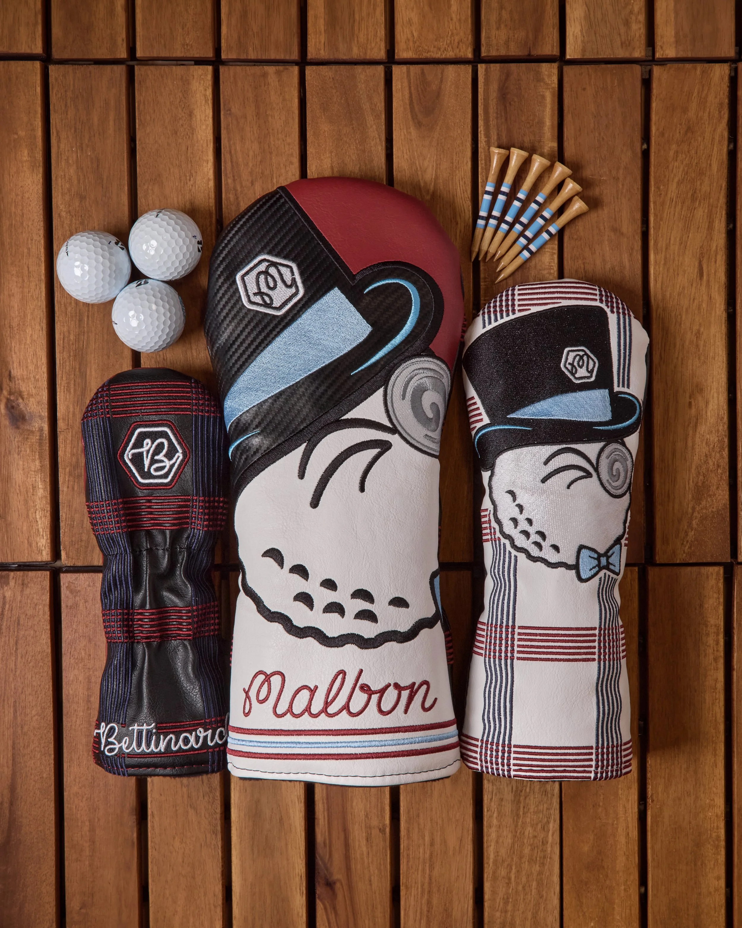 A collection of golf head covers designed as cartoon skulls, bathroom, and plaid pattern, hanging on a wooden wall.