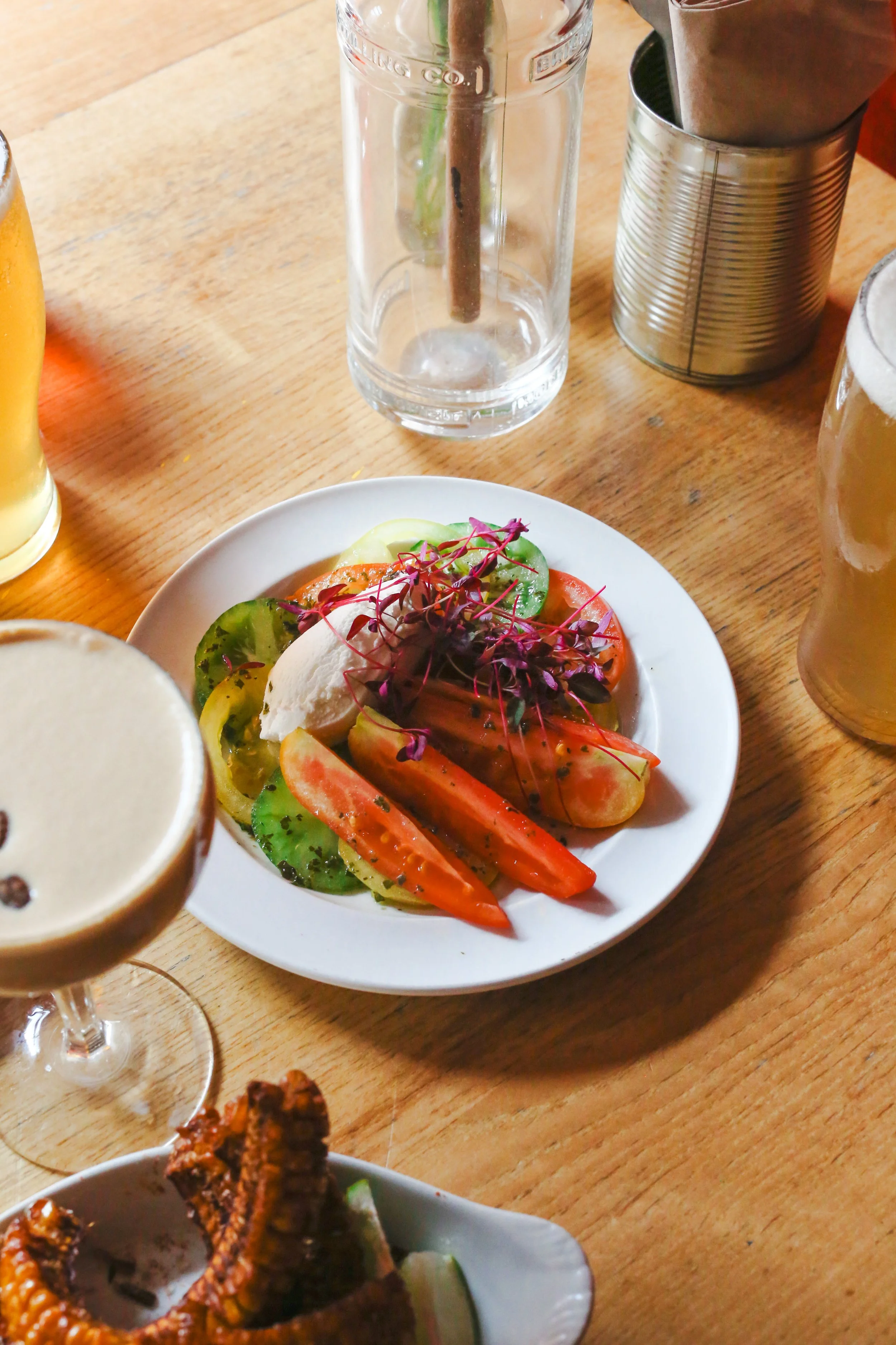 A table with a vegetarian salad, glass of beer, and a glass of water with a straw.