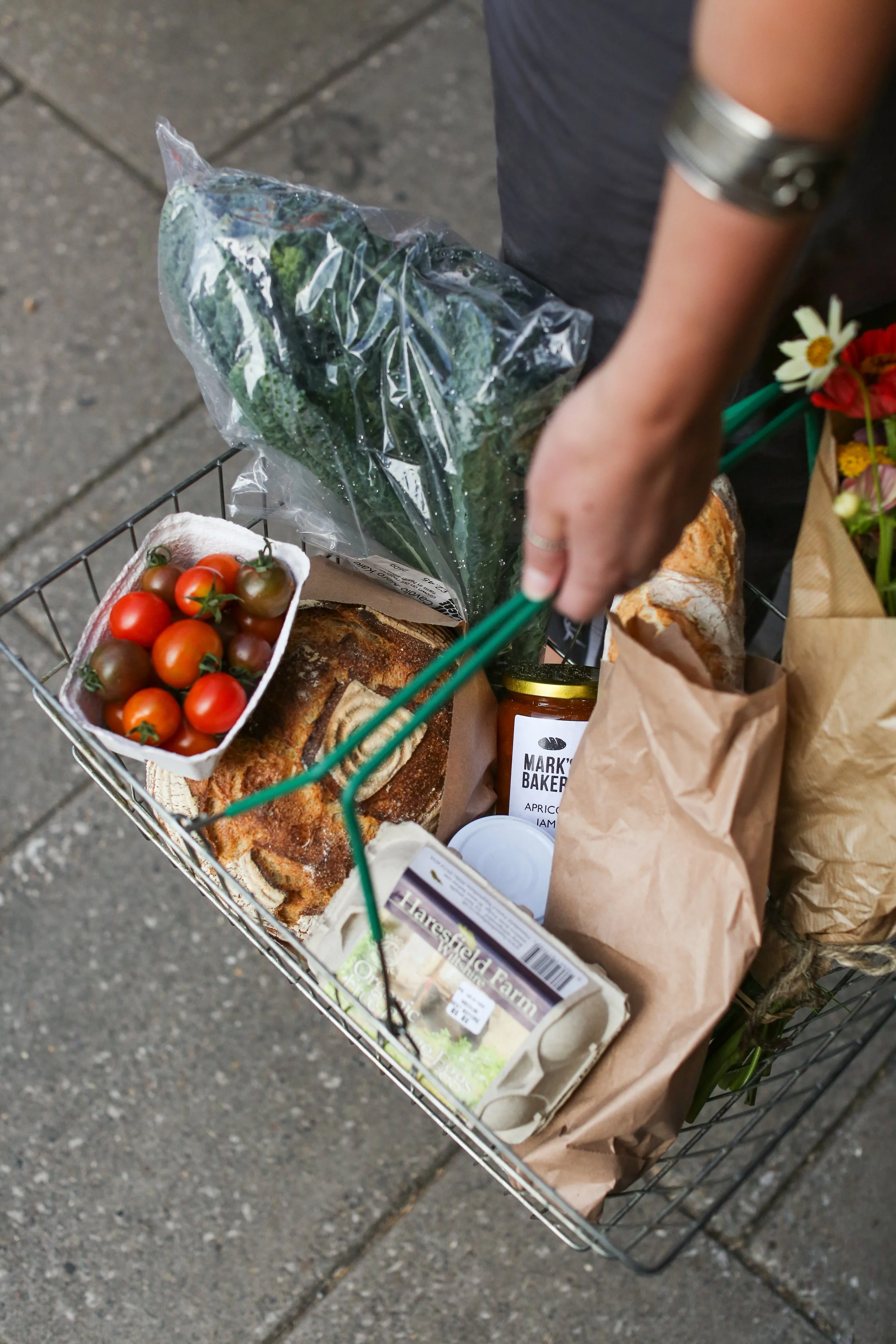 A shopping cart filled with fresh produce bought at the farm shop inside Mark's Bakery Baked goods, flowers, and grocery items.