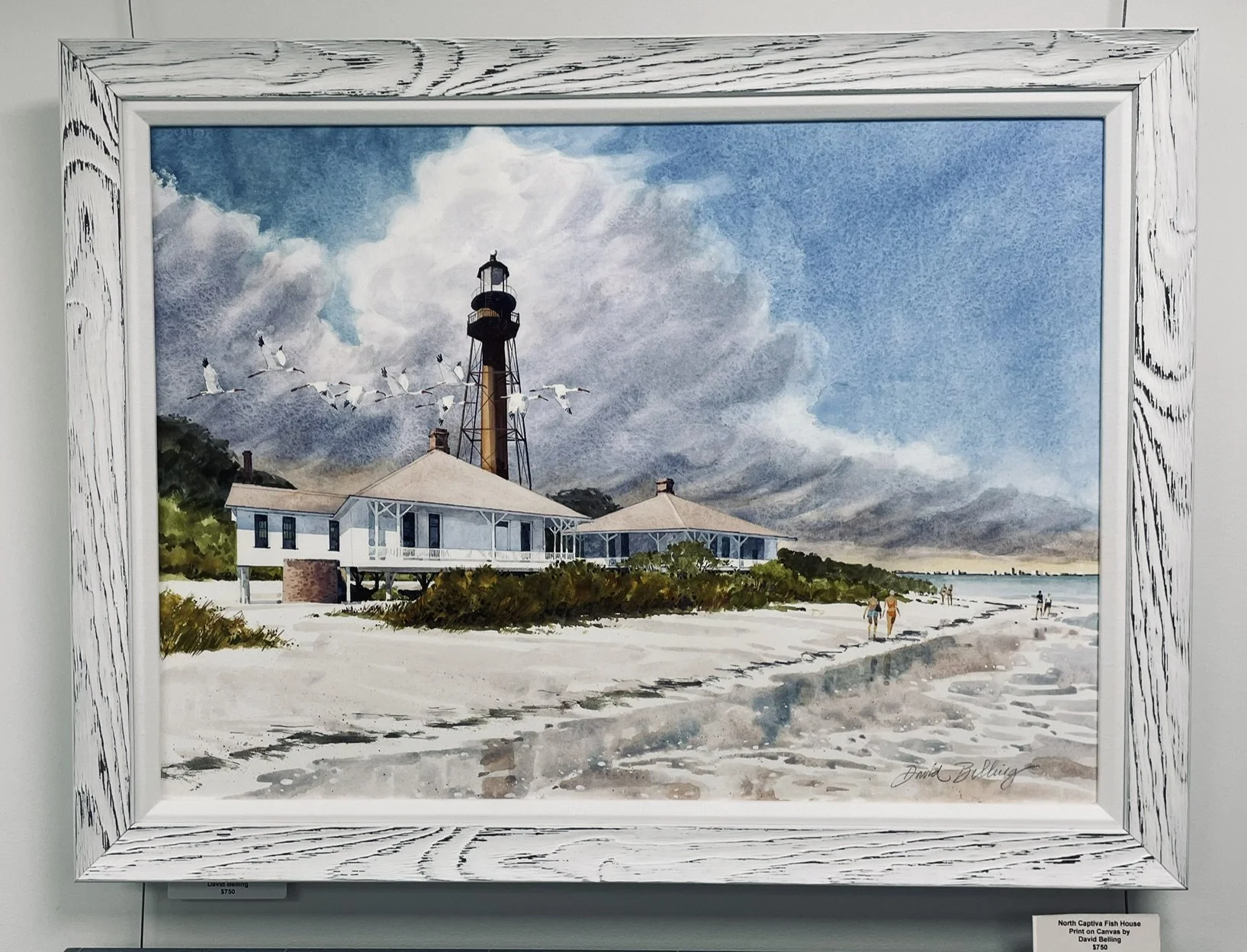 Watercolor painting of a lighthouse by the beach, with a white house, seagulls flying overhead, and people walking along the shoreline under a partly cloudy sky.