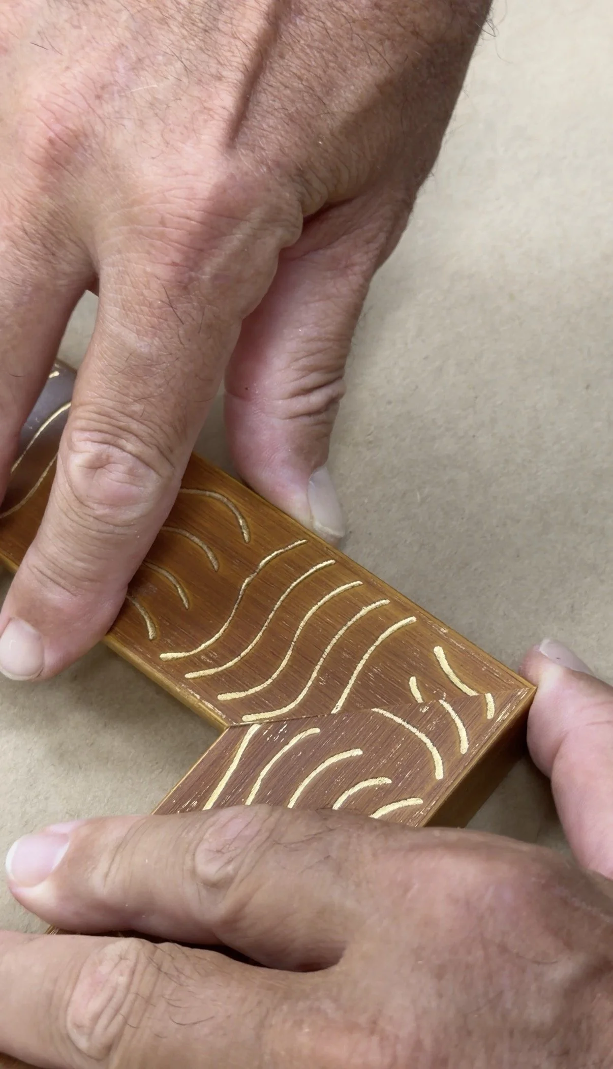 Close-up of hands assembling a wooden puzzle with intricate carved patterns on a brown surface.