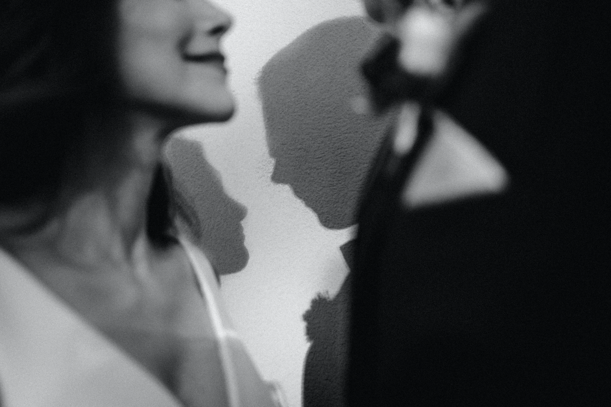 Two people close to each other, appearing to be about to kiss, with their faces and noses nearly touching, in a black and white photograph.