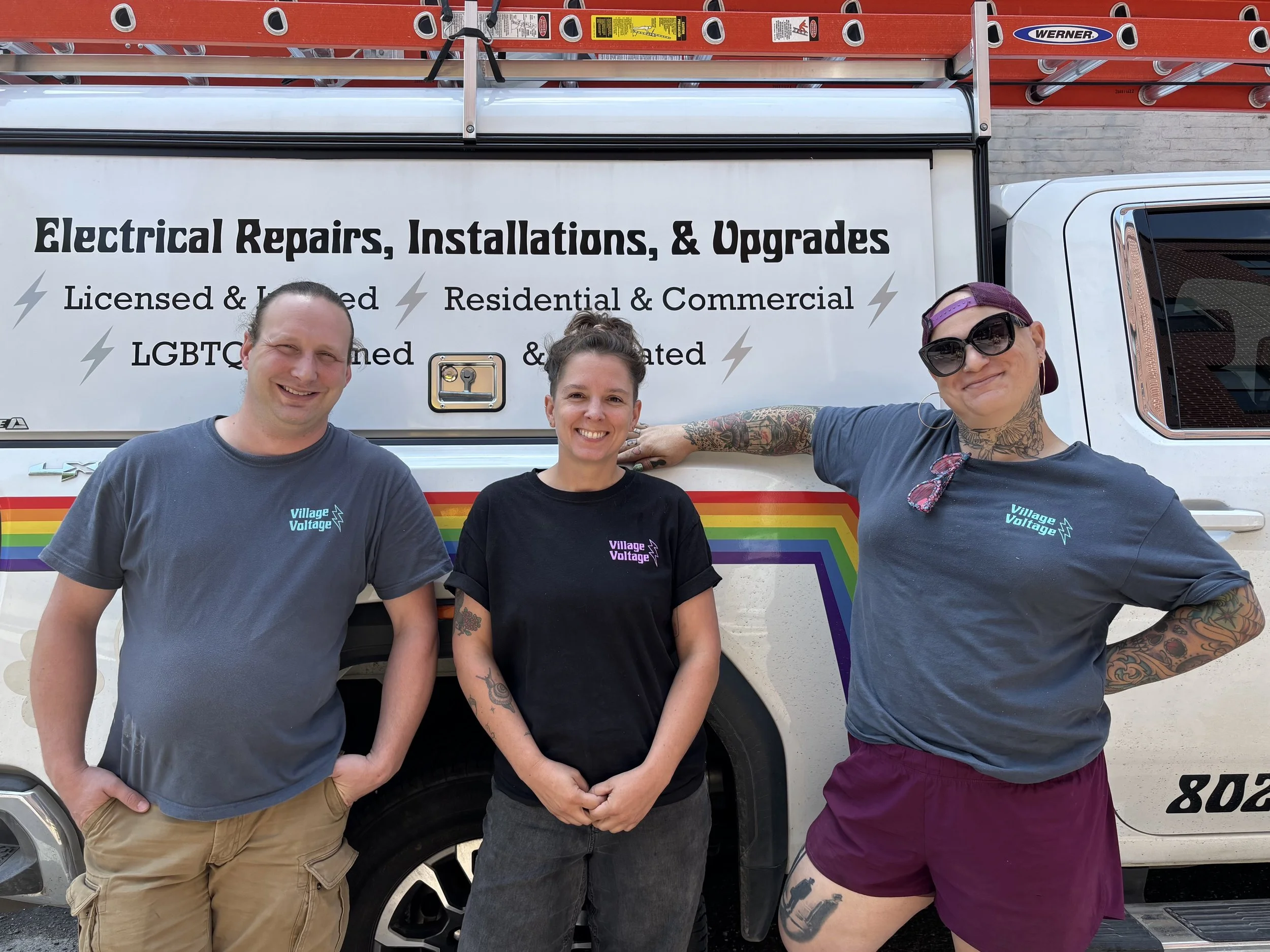 Three people standing in front of a white vehicle with a sign that says 'Electrical Repairs, Installations, & Upgrades'.