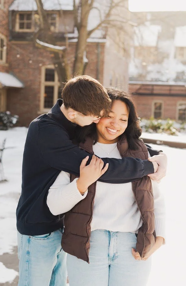 A young man hugging a smiling woman outdoors in a winter setting.