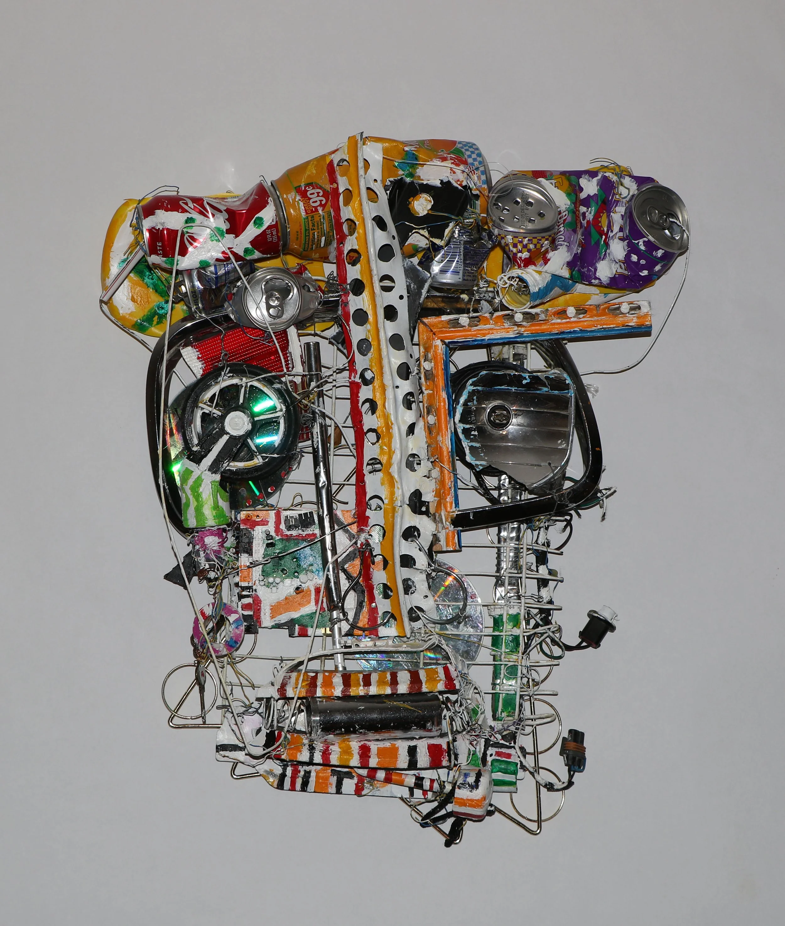 Found object sculpture by Karl A. McIntosh featuring recycled cans, wires, salvaged metal parts, and colorful mixed-media elements arranged in an abstract composition.v