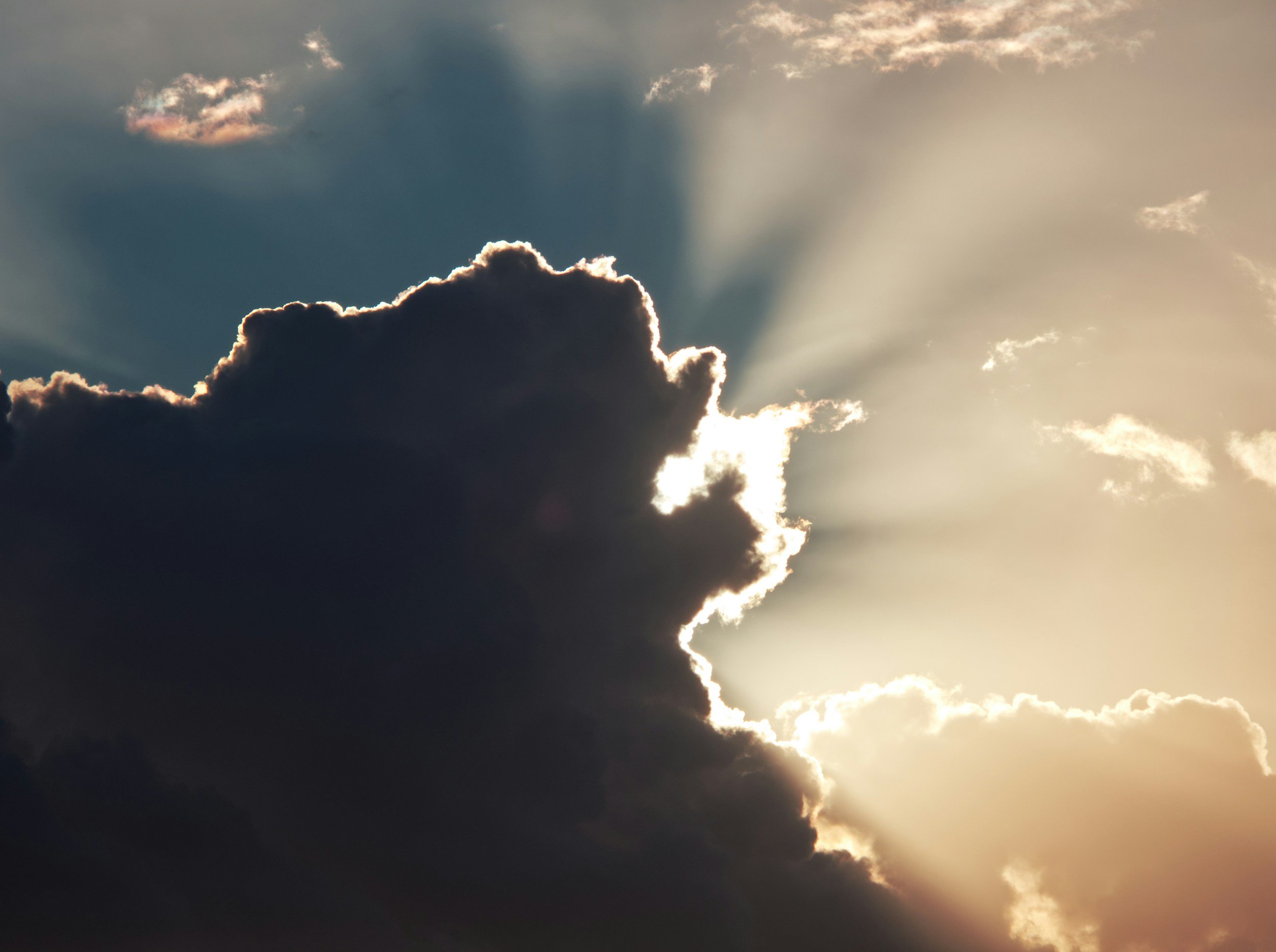 Sunlight streaming through dark clouds in a partly cloudy sky.