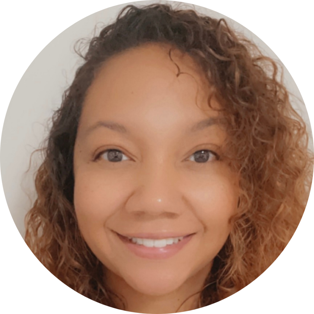 Close-up portrait of a smiling woman with curly hair, light makeup, and a plain background.