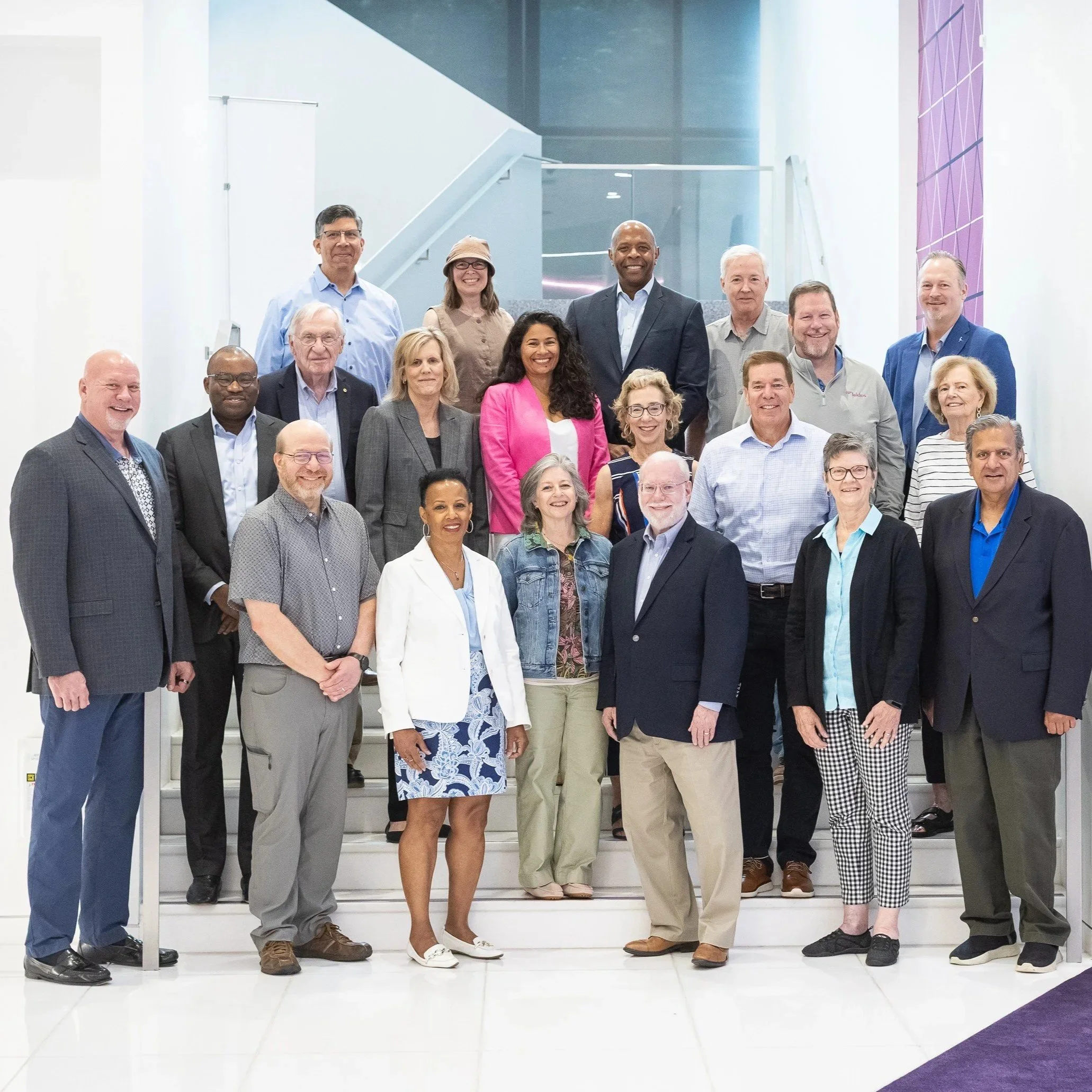 The Cornerstones FY 2027 Board of Directors, a diverse group of professionally dressed people standing on the staircase of the beautiful, modern Leidos headquarters building in Reston Town Center.