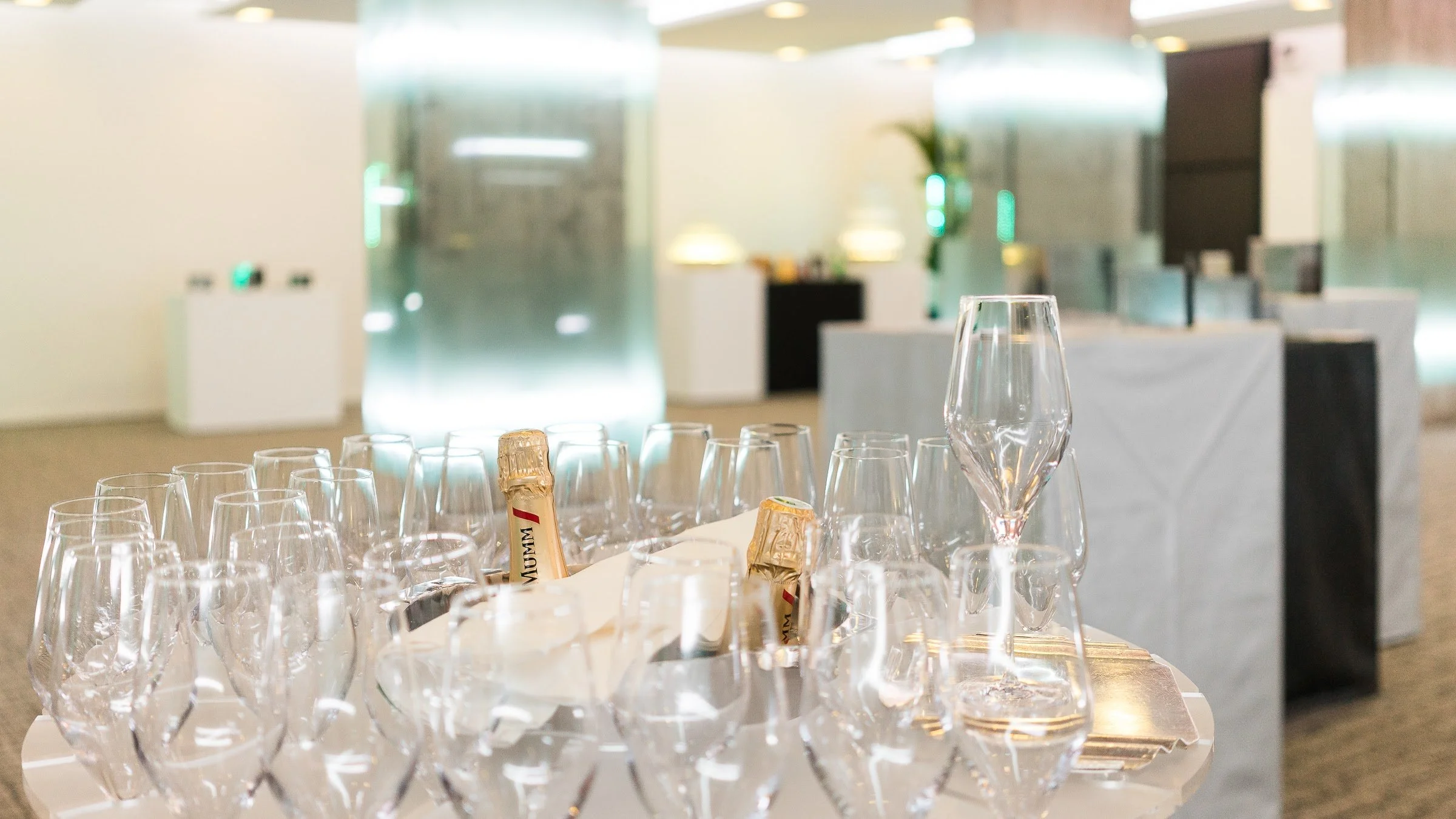 Verres à champagne et bouteilles de champagne sur une table, dans un espace de réception élégamment décoré.
