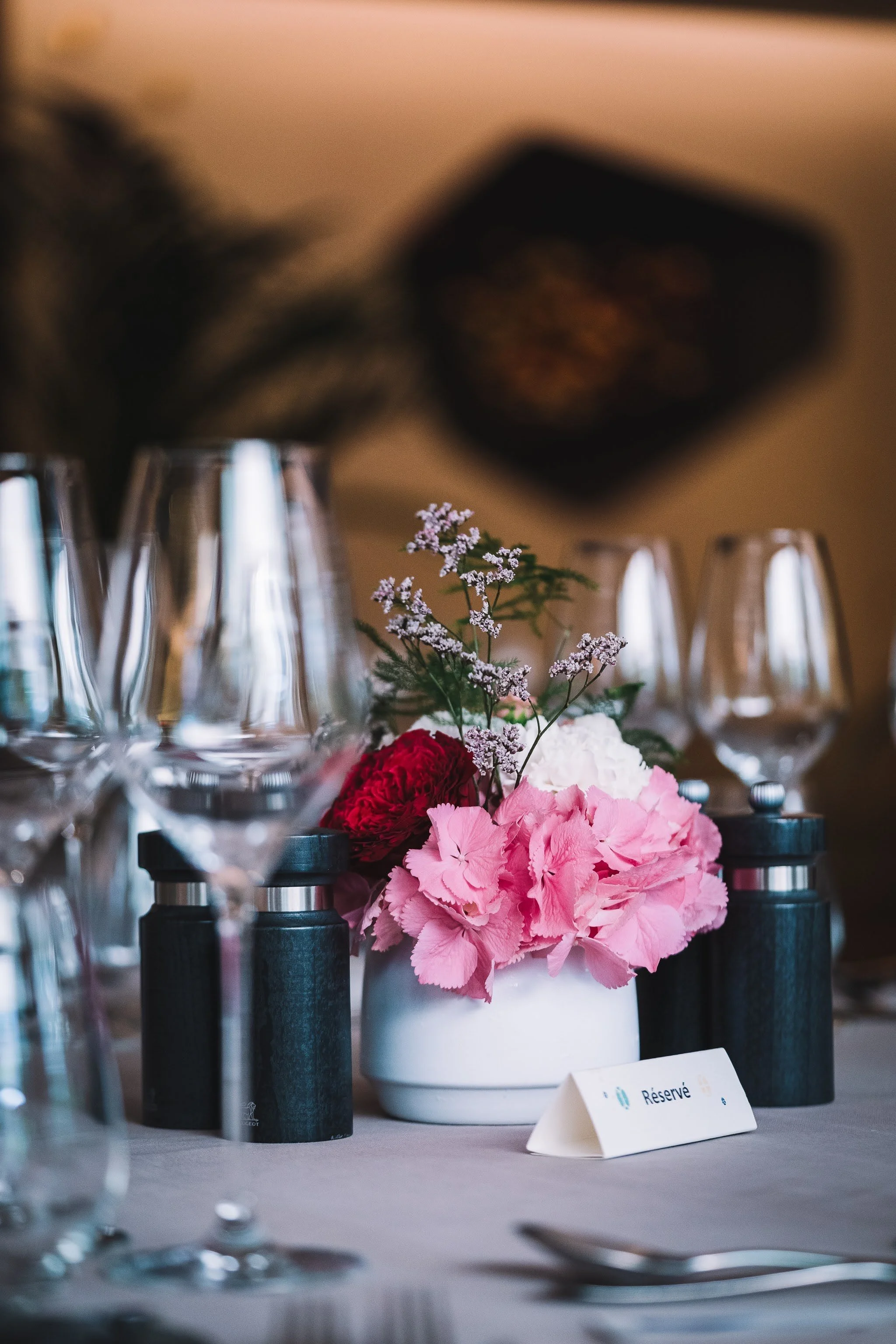 Une table de réception décorée avec un centre de table de fleurs, des verres à vin, et une carte «Réservé».