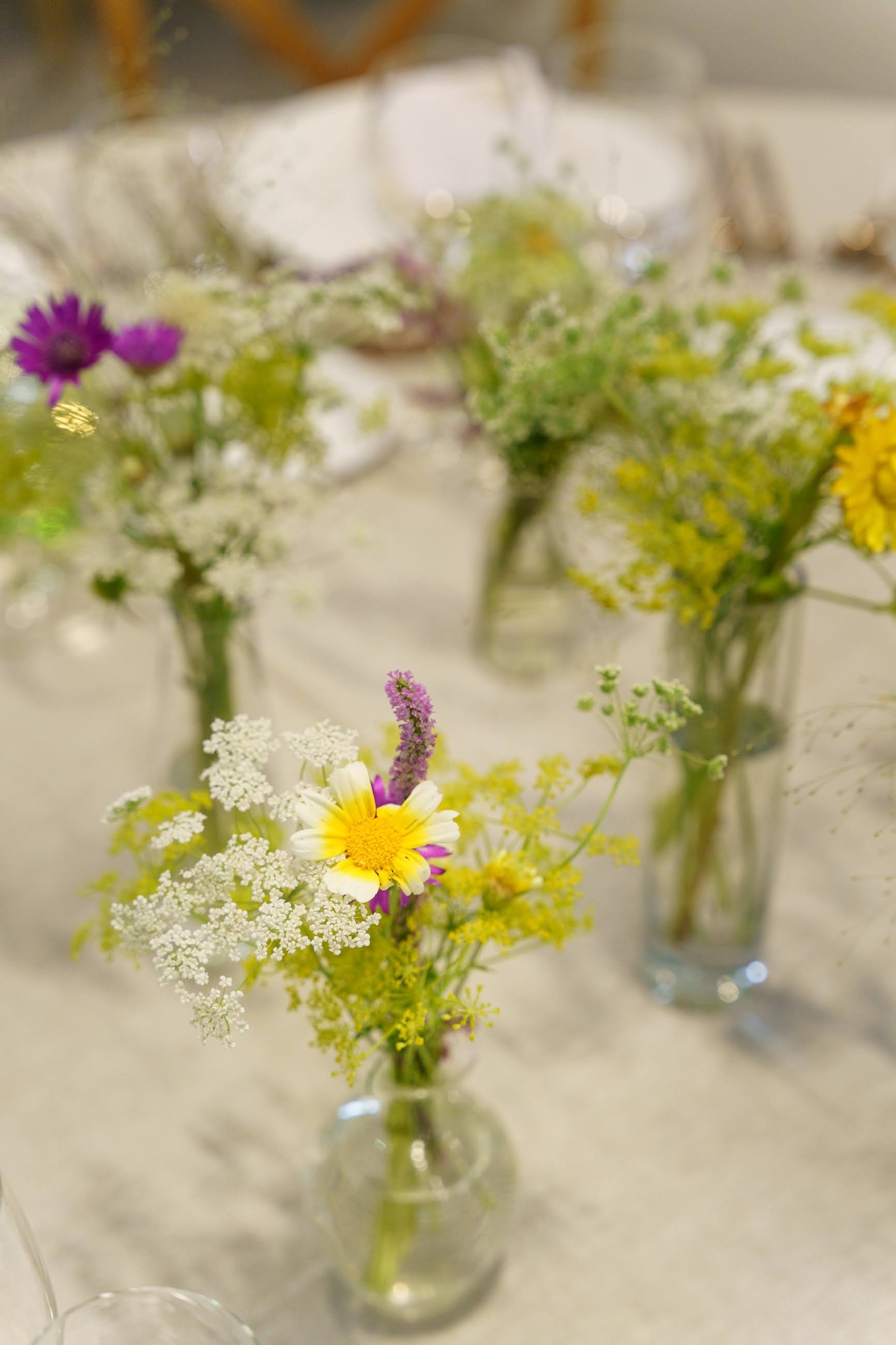 Fleurs sauvages colorées dans un vase en verre transparent sur une table de bois.