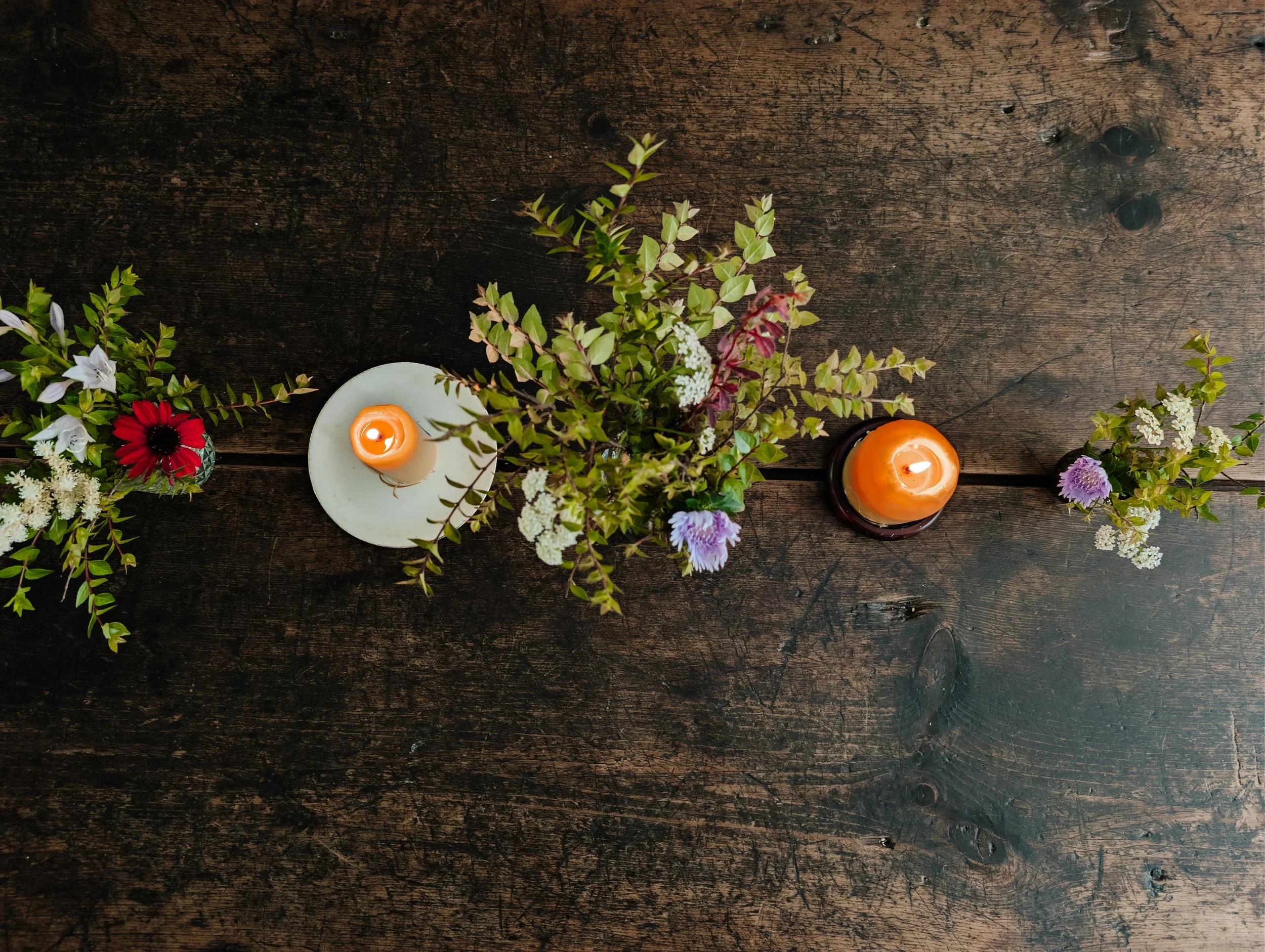 Flowers and candles on a rustic wooden table.