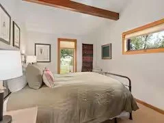 Bedroom with bed, pillows, window, and door leading outside.
